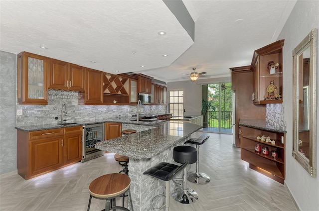 kitchen with beverage cooler, brown cabinets, dark stone countertops, and open shelves