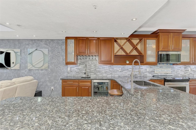 kitchen with glass insert cabinets, beverage cooler, appliances with stainless steel finishes, and dark stone counters