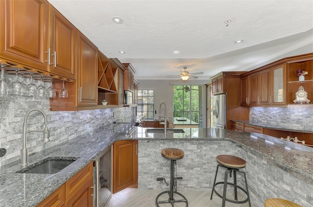 kitchen with stainless steel fridge with ice dispenser, light stone countertops, a kitchen bar, open shelves, and a sink