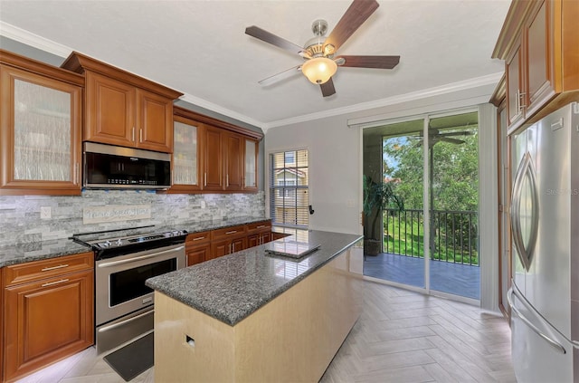 kitchen featuring a center island, brown cabinets, appliances with stainless steel finishes, glass insert cabinets, and dark stone counters