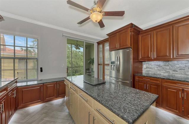 kitchen with dark stone countertops, a center island, a healthy amount of sunlight, and stainless steel fridge with ice dispenser