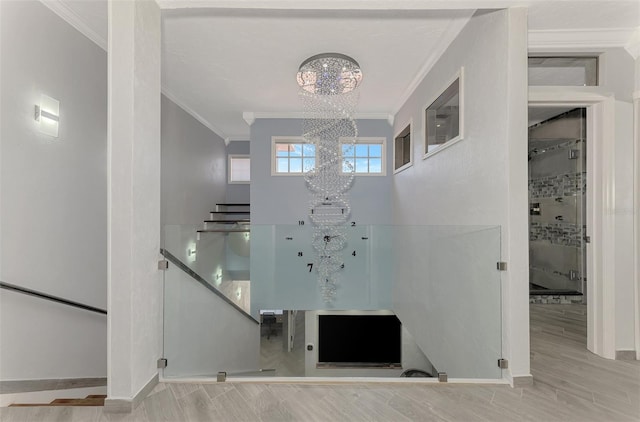 interior space featuring baseboards, stairway, wood finished floors, an inviting chandelier, and crown molding