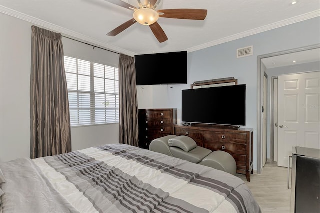 bedroom featuring visible vents, crown molding, light wood-style flooring, and ceiling fan