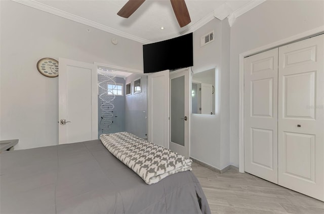 bedroom featuring visible vents, light wood-style flooring, ceiling fan, ornamental molding, and a closet