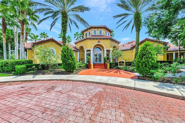 mediterranean / spanish-style home featuring a tile roof, french doors, and stucco siding