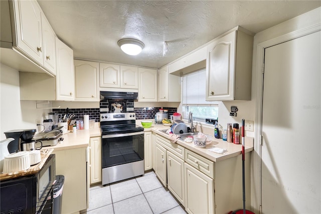 kitchen featuring light tile patterned flooring, sink, electric range, and decorative backsplash