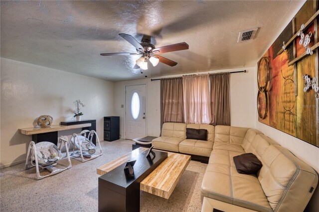 living room with ceiling fan, carpet, and a textured ceiling