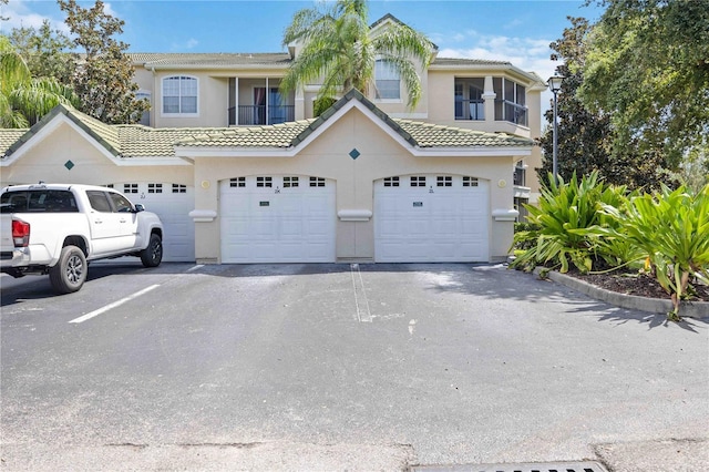 view of property featuring a garage, aphalt driveway, and stucco siding