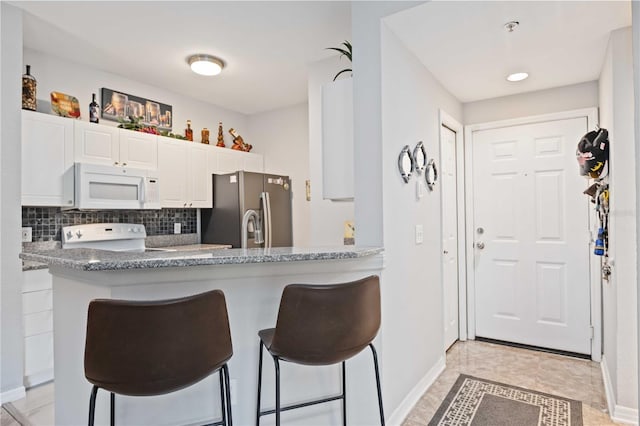 kitchen with range, stainless steel fridge with ice dispenser, white microwave, a peninsula, and white cabinetry