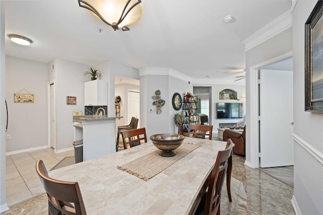 tiled dining area featuring ceiling fan and crown molding