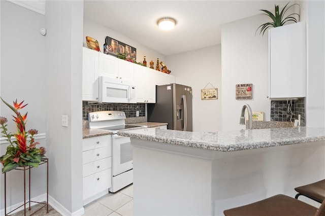 kitchen featuring white appliances, white cabinets, a peninsula, and a kitchen breakfast bar