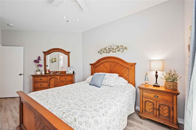 bedroom with ceiling fan, vaulted ceiling, and light hardwood / wood-style flooring