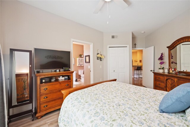 bedroom featuring ceiling fan, ensuite bathroom, visible vents, a closet, and light wood finished floors