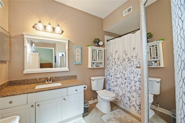 bathroom featuring tile patterned flooring, toilet, vanity, and walk in shower