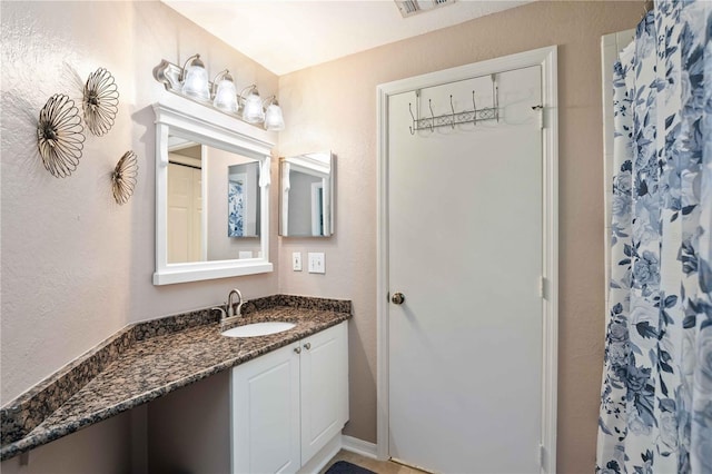 bathroom with visible vents, walk in shower, and vanity