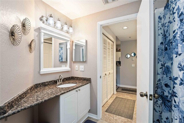 bathroom featuring tile patterned flooring, visible vents, vanity, baseboards, and a closet