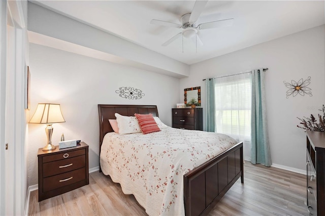 bedroom with a ceiling fan, light wood-style flooring, and baseboards