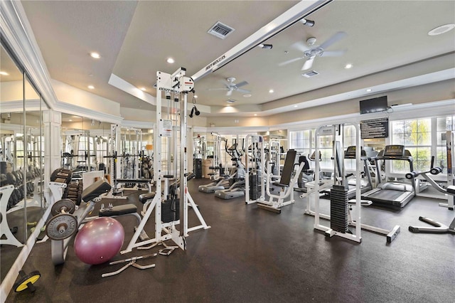 exercise room with ceiling fan and a tray ceiling