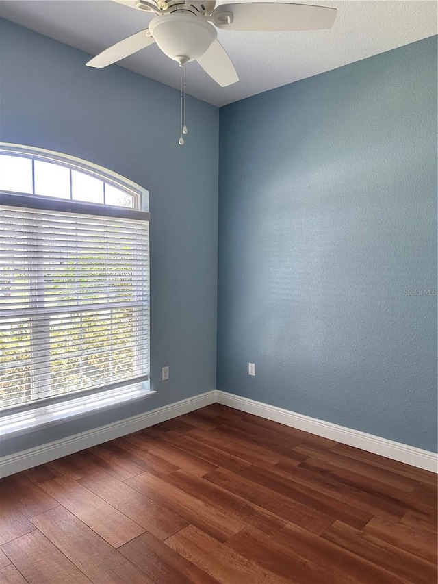 empty room featuring plenty of natural light, ceiling fan, and hardwood / wood-style flooring