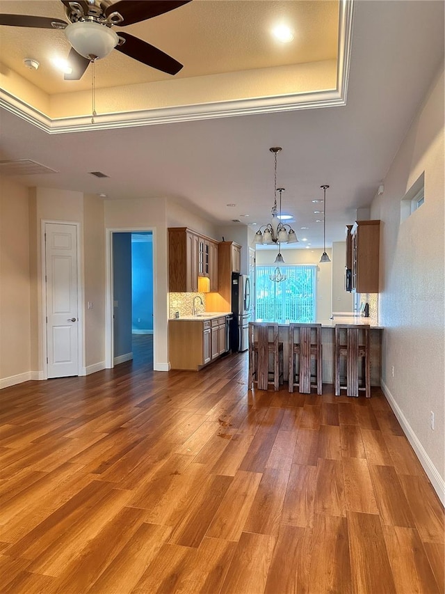 unfurnished living room with ceiling fan with notable chandelier, hardwood / wood-style floors, and sink