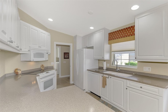 kitchen featuring white appliances, recessed lighting, a sink, and white cabinets