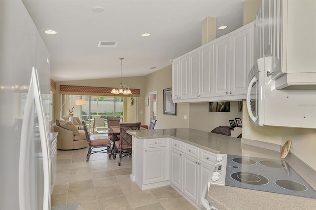 kitchen with white fridge, kitchen peninsula, white cabinets, and hanging light fixtures