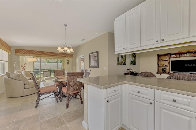 kitchen featuring white cabinets, vaulted ceiling, a chandelier, kitchen peninsula, and pendant lighting