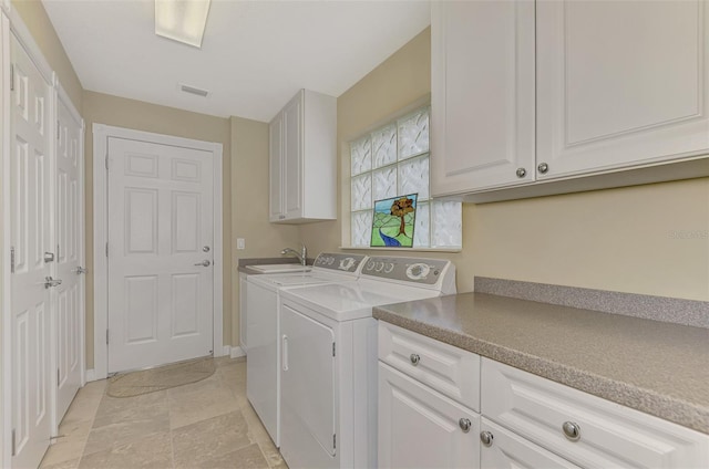 clothes washing area featuring cabinets and independent washer and dryer