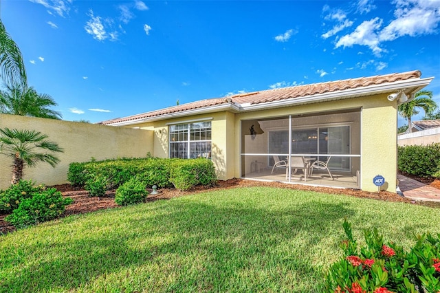 rear view of property with a yard, a patio, and a sunroom