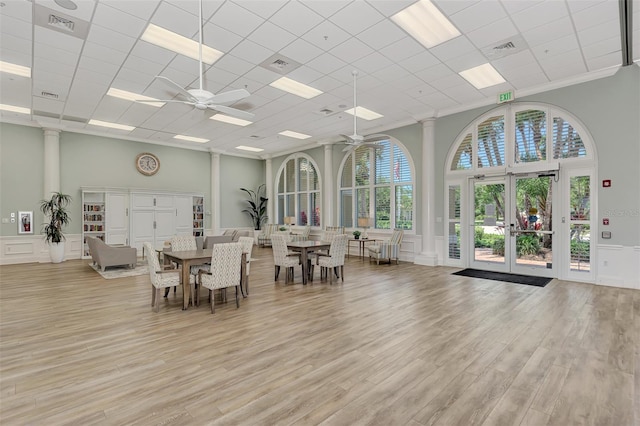 dining area with a ceiling fan, decorative columns, a towering ceiling, and light wood-style floors