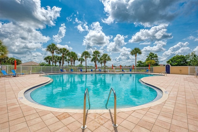 pool with a patio area and fence