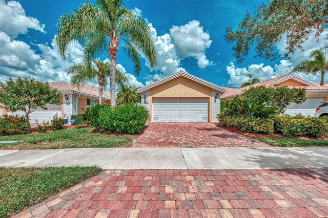 view of front of house with a garage, decorative driveway, and stucco siding