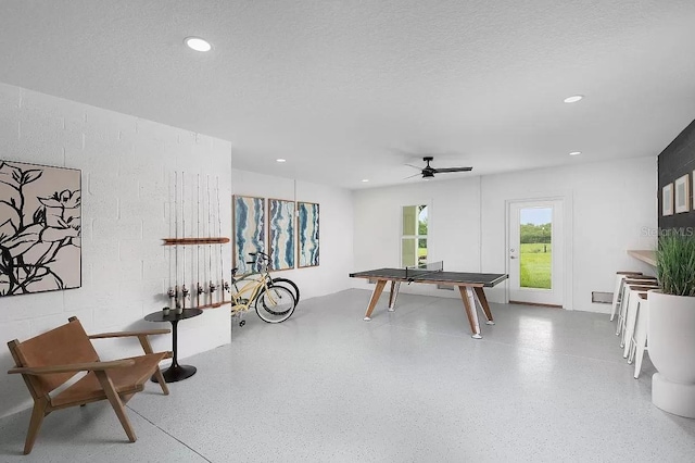 recreation room with a textured ceiling and ceiling fan