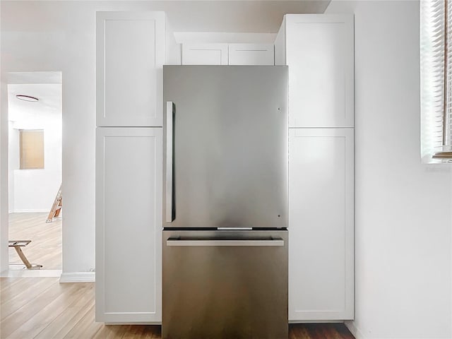 kitchen with white cabinets, light wood-type flooring, and stainless steel fridge