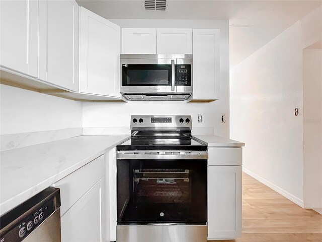 kitchen with appliances with stainless steel finishes, light hardwood / wood-style flooring, and white cabinetry