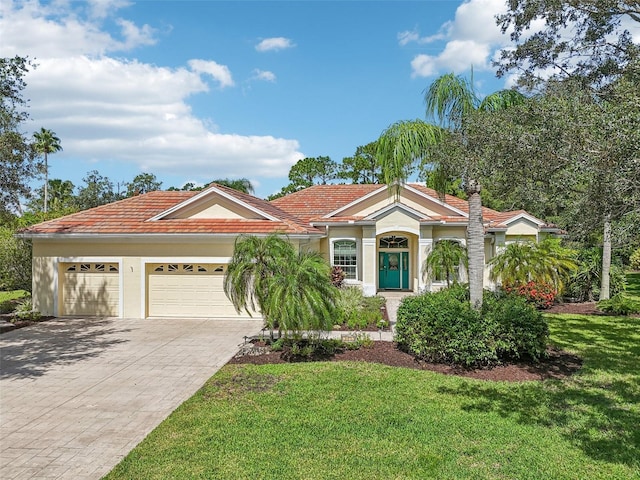 mediterranean / spanish home featuring stucco siding, a front yard, decorative driveway, and a garage