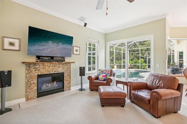 carpeted living room with ceiling fan, crown molding, and a tile fireplace