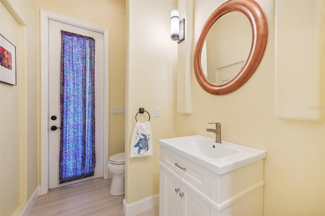 bathroom with toilet, hardwood / wood-style floors, and vanity