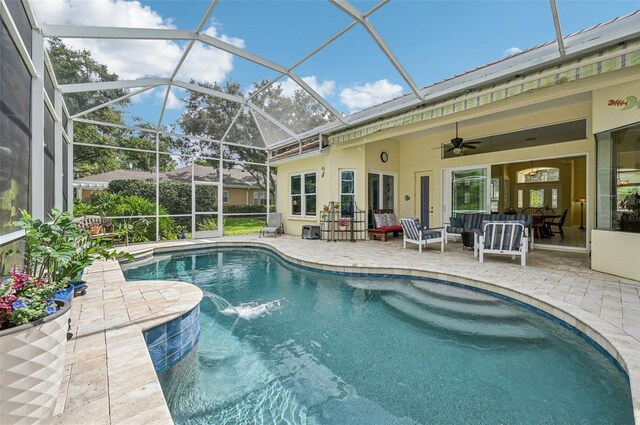 view of pool with ceiling fan, glass enclosure, a patio area, and pool water feature