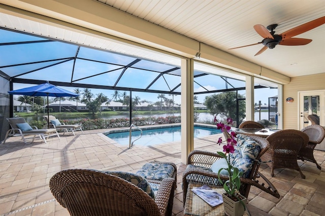 view of pool with a water view, ceiling fan, a patio area, and glass enclosure