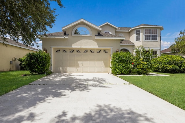 traditional-style house with driveway, a garage, a front lawn, and stucco siding