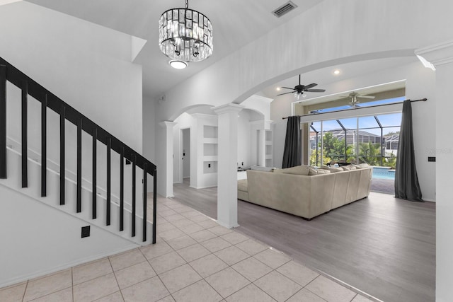 living room featuring visible vents, arched walkways, a sunroom, ceiling fan, and light wood-style floors