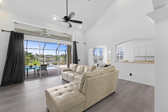 living room with high vaulted ceiling, a ceiling fan, a sunroom, and wood finished floors