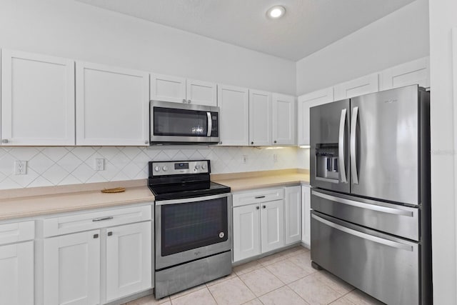 kitchen with light countertops, appliances with stainless steel finishes, backsplash, and white cabinetry