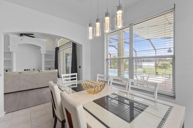 dining space with arched walkways, ceiling fan, and light tile patterned floors