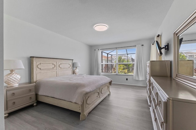 bedroom with dark wood-style floors, multiple windows, and baseboards