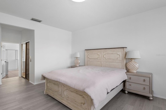 bedroom featuring wood finished floors, visible vents, and baseboards