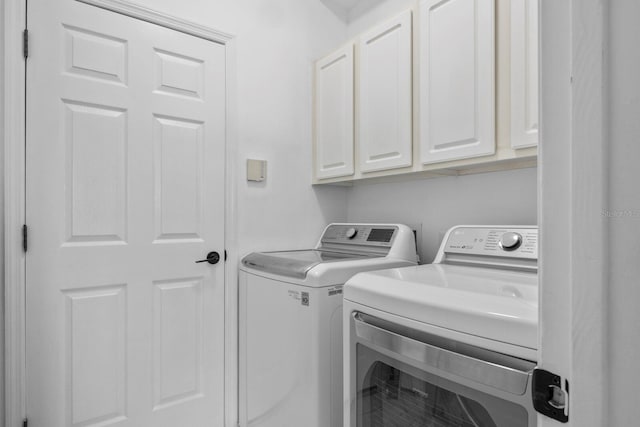 clothes washing area featuring washing machine and dryer and cabinet space