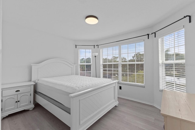 bedroom with light wood-type flooring and baseboards