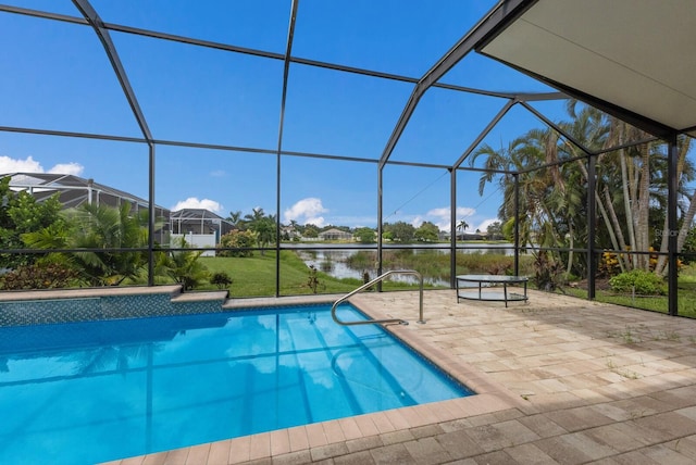 pool with a patio area, glass enclosure, and a water view